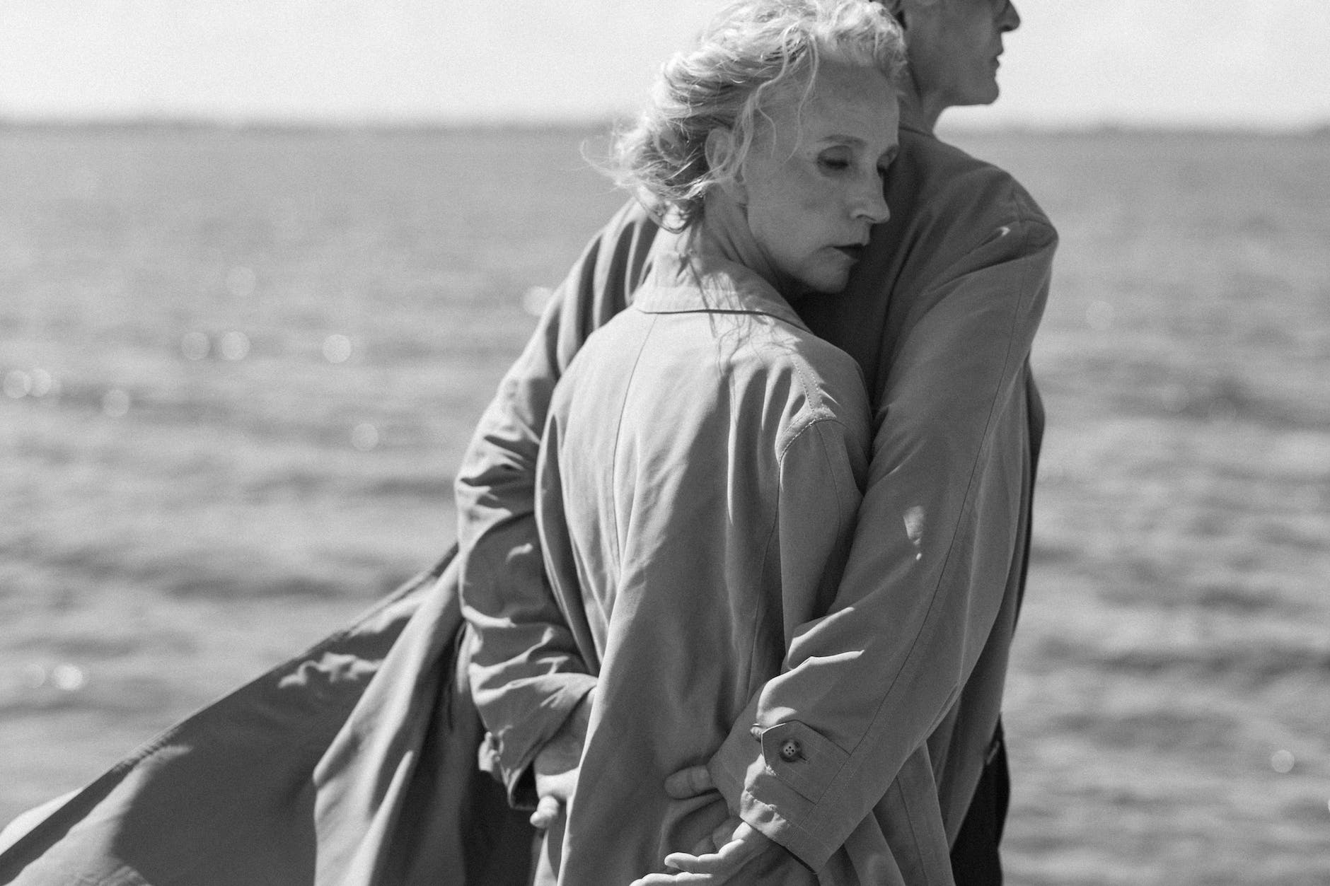 grayscale photo of two people in trench coats